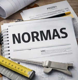 Compendio de normas técnicas de construcción acompañado de herramientas de medición y planos de proyecto.